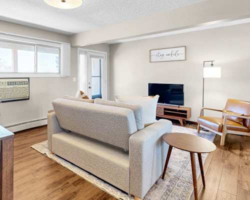 A living room with a grey couch, a wooden table, and a television.