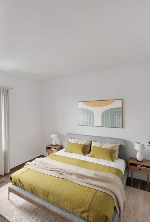 A bedroom with a large bed and a potted plant.