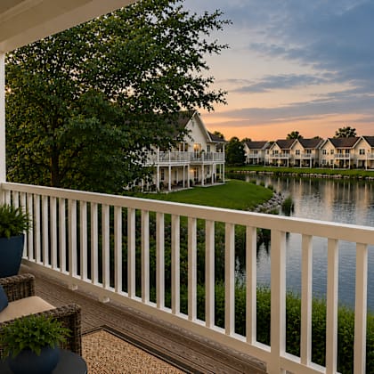 A balcony with a chair and table overlooking a body of water.