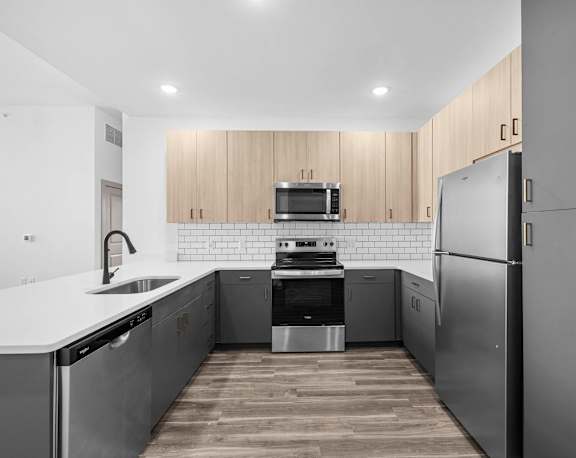 A kitchen with wooden cabinets and a stainless steel dishwasher.