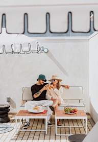 Two people sitting on a white bench with a table in front of them.at 810 Ashland, California