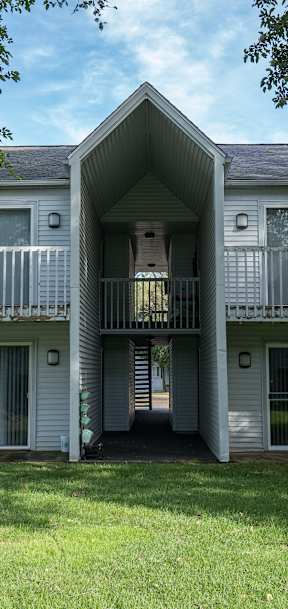 A white building with a balcony and a door in the center.