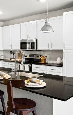 a kitchen with white cabinets and a black counter top