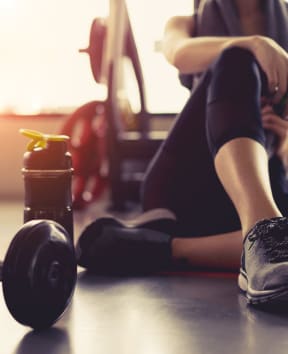 woman in gym with water bottle and weights