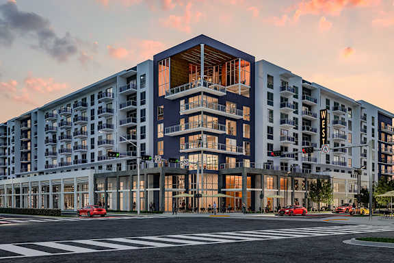 A modern multi-story building with a large glass facade and a red car parked in front.