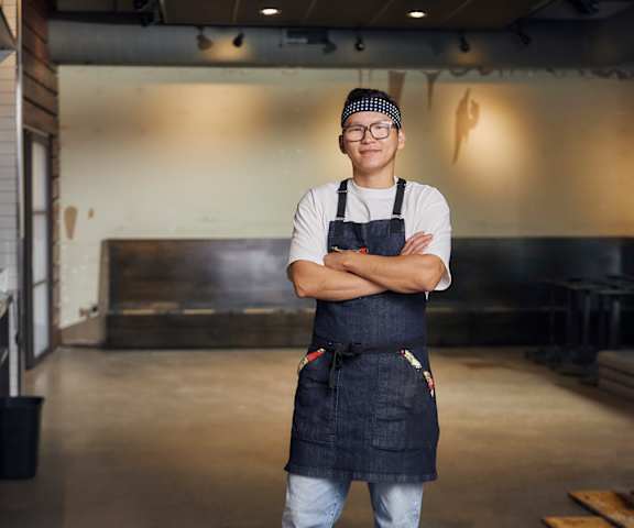 Chef Baaska Tegshbileg posing with arms crossed in his unfinished restaurant.