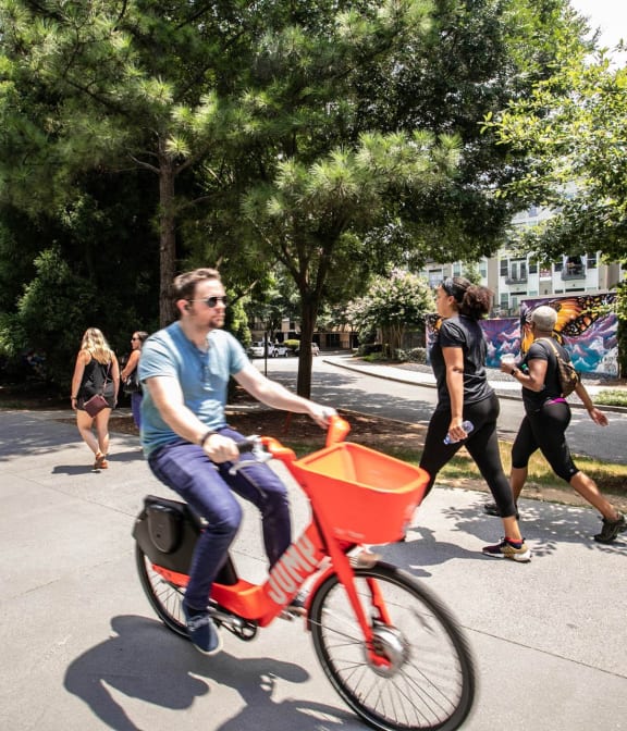 Man riding bike on The Atlanta Beltline, adults in background excersing and walking on beltine in Atlanta, GA