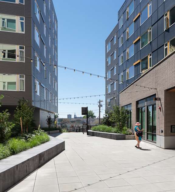 a man walking down a sidewalk next to a building at Cedar Crossing, Seattle, WA, 98115