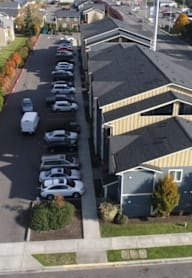 A parking lot with cars and a building with a yellow and grey exterior.