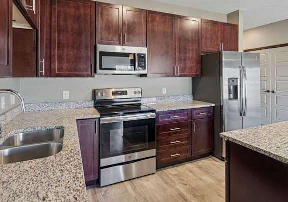 A kitchen with brown cabinets and granite countertops.