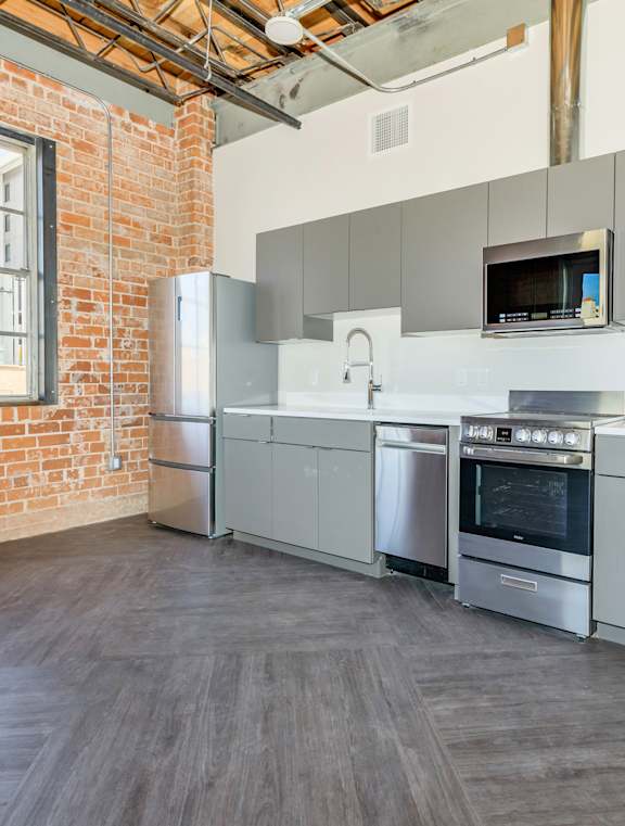 A large empty room with a brick wall and wooden flooring.