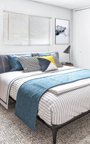 a bedroom with white walls and a bed with blue blankets and pillows
