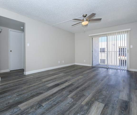 an empty living room with wood flooring and a ceiling fan