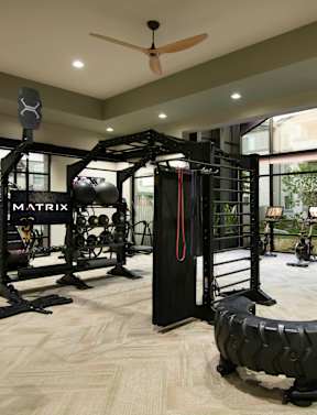 a spacious fitness room with cardio equipment and weights