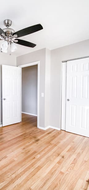 an empty living room with wood floors and a ceiling fan