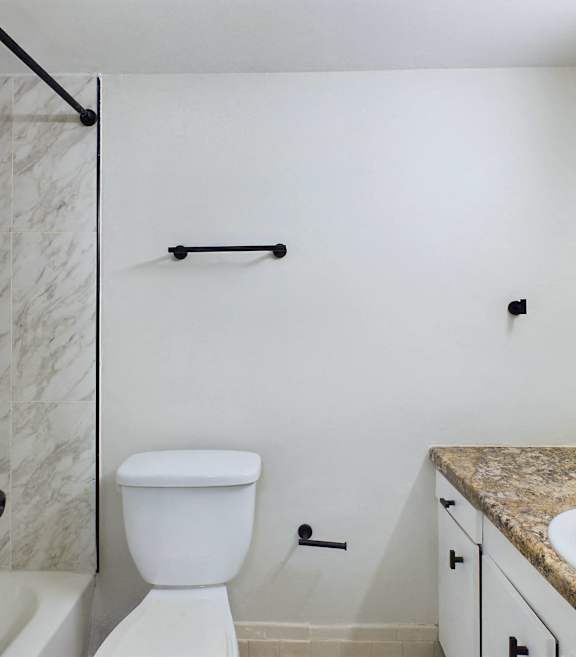 A white toilet sits in a bathroom next to a sink.