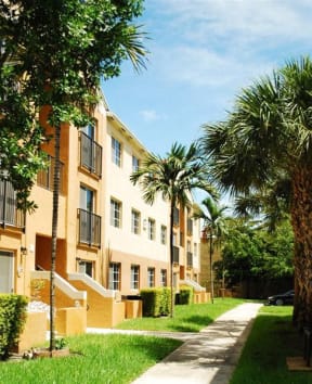 a row of apartment buildings with palm trees at Marbrisa Apartments, Miami Gardens