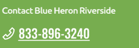 A green sign with a phone number for Blue Heron Riverside.