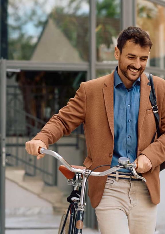 a man in a brown jacket riding a bike