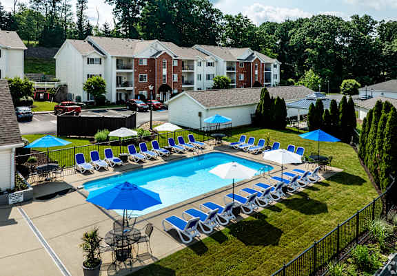 A swimming pool surrounded by lawn chairs and umbrellas.