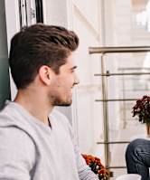 A man and a woman are sitting on a balcony with a cup in their hands.