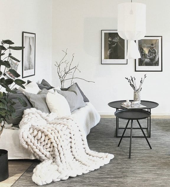 A living room with a white couch and black chairs.