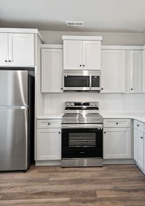 A modern kitchen with white cabinets and stainless steel appliances. at Ovation at Town Madison, Madison