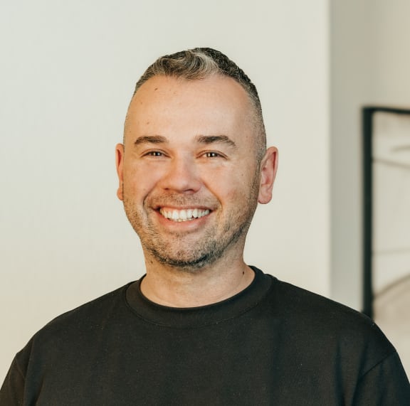 a man in a black shirt smiles at the camera