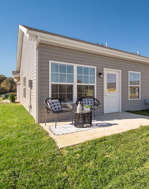 A row of houses with a patio and chairs in front.