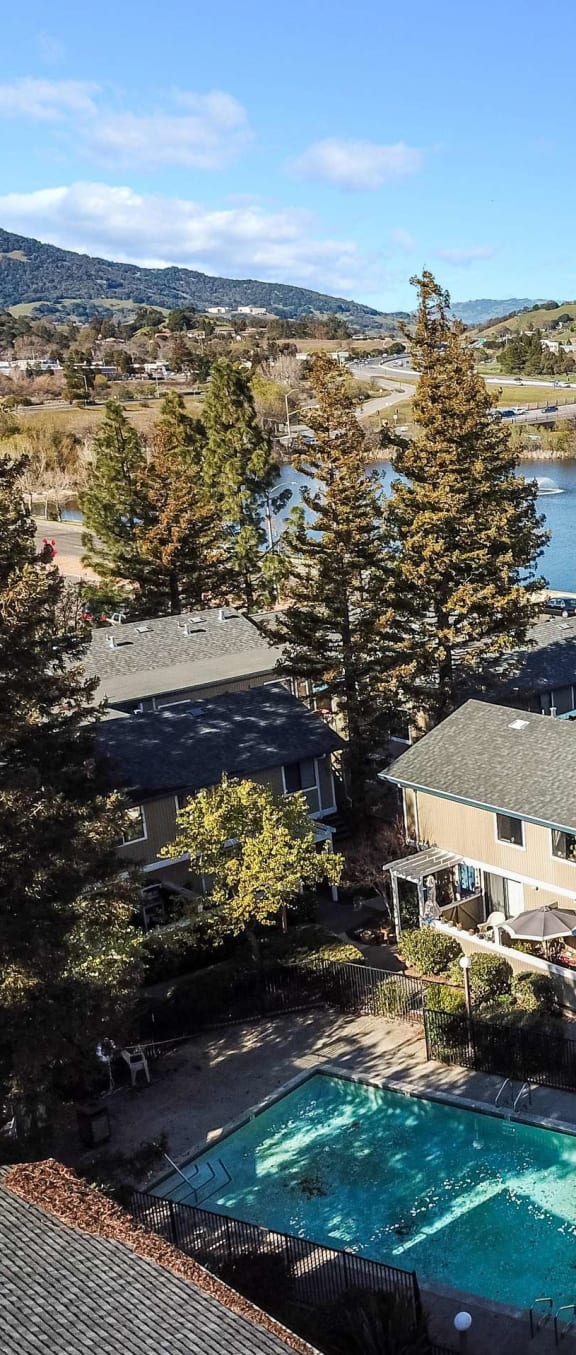 aerial view of apartment buildings, pool, and lake