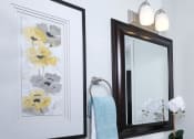 Thumbnail 9 of 23 - Bathroom in Fifteen 50 Apartments Las Vegas with floral art, vanity mirror, and sink with storage.