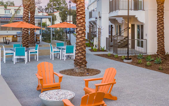 A patio with orange chairs and palm trees.