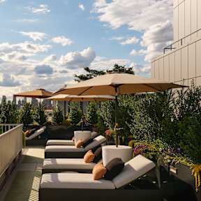 A rooftop patio with lounge chairs and umbrellas overlooking a city skyline.