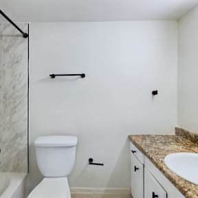 A white toilet sits in a bathroom next to a sink.