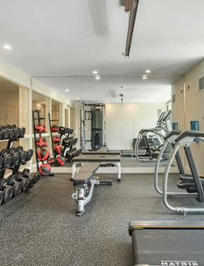 A gym with a variety of equipment including treadmills, weights, and exercise machines.