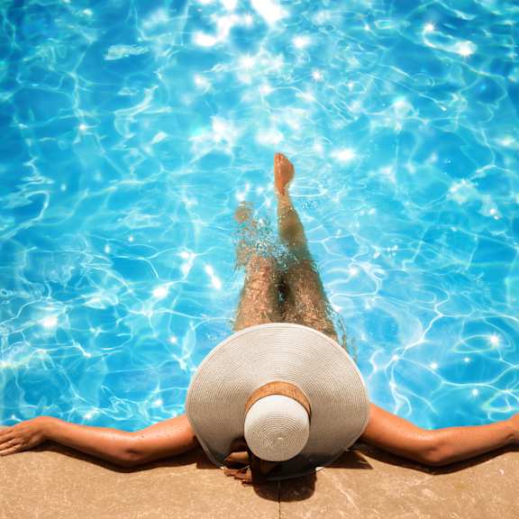 A person wearing a white hat is floating in a pool.