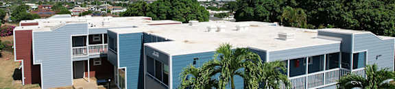 A blue and red building with a white roof and a green lawn in front.
