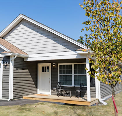 the front of a white and gray house with a tree