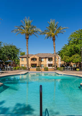 a swimming pool with chaise lounge chairs and umbrellas in front of a hotel