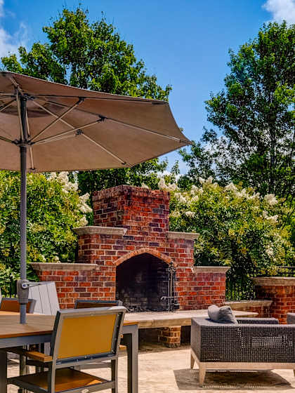 A patio with a table, chairs, and umbrellas.