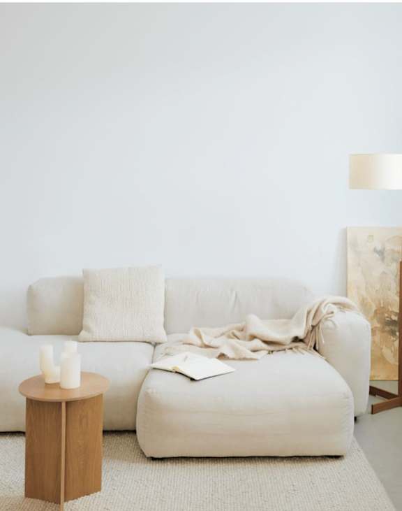 A living room with a white couch, a wooden side table, and a floor lamp.