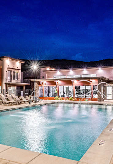 A swimming pool area with lounge chairs and a building in the background.