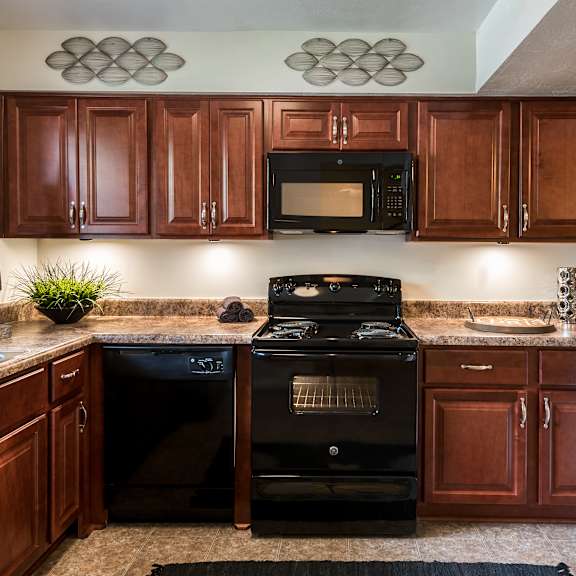 A kitchen with brown cabinets and black appliances.