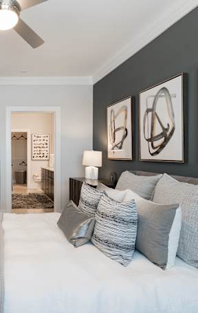 A bedroom with a large bed, a dresser, and a mirror.
