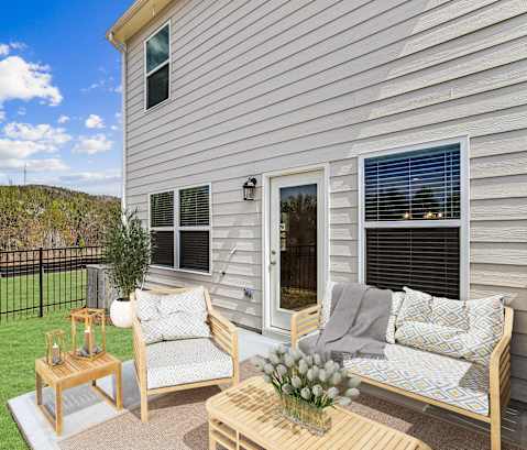a patio with two chairs and a table in front of a house