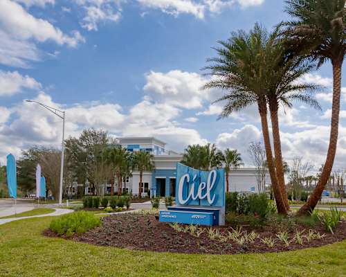 A blue sign with the word "Ciel" on it is in the foreground of a well-maintained garden.