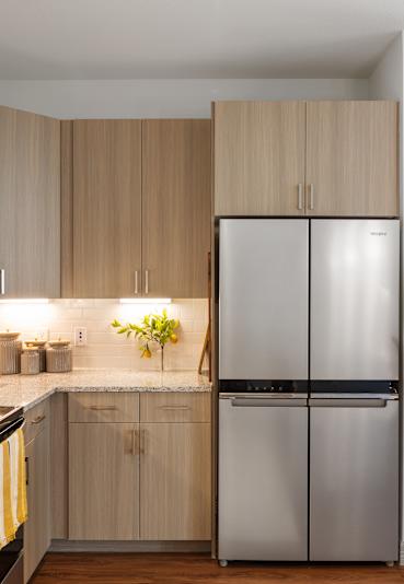 A kitchen with wooden cabinets and a stainless steel refrigerator.