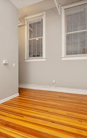 A room with a wooden floor and a window with blinds.