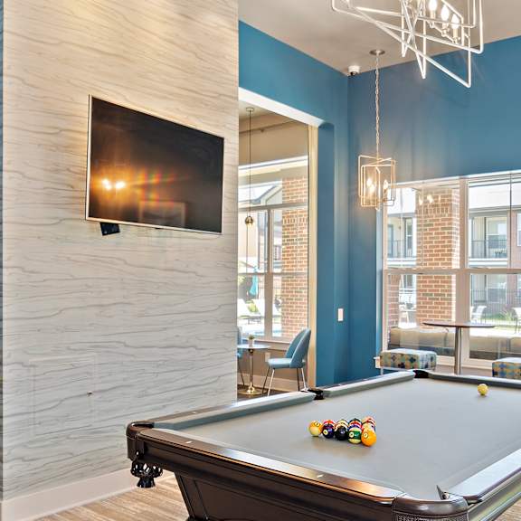 A pool table is in the middle of a room with blue walls.