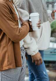 Two people talking and holding coffee in hand at Harrisburg Lofts, Houston, TX